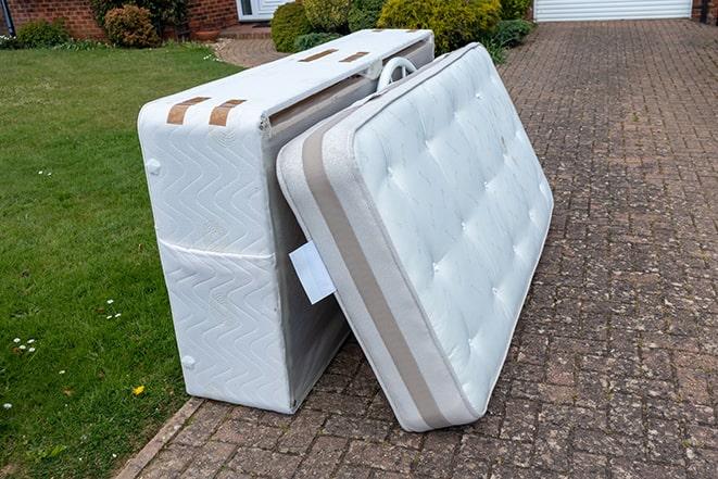 old, stained mattress being loaded onto a pickup truck